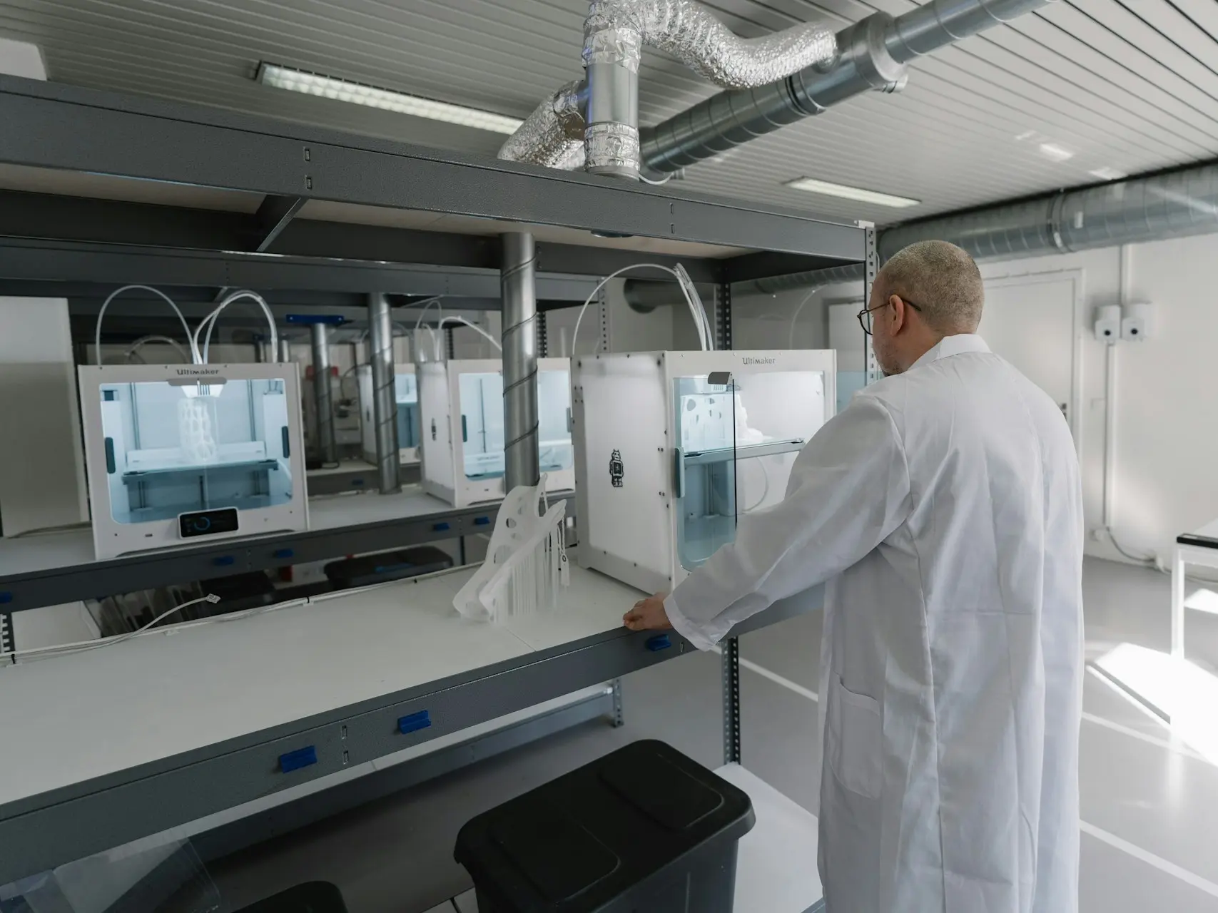 Man in a lab coat using a 3d printer