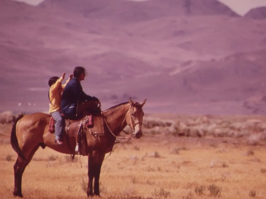 An old image of a woman and child on horseback in the desert