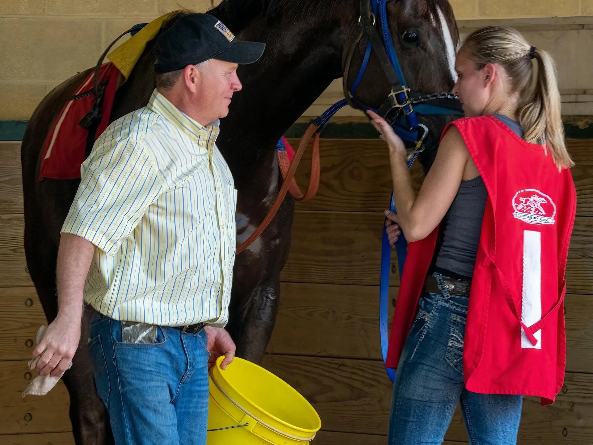 man with a bucket standing with a horse