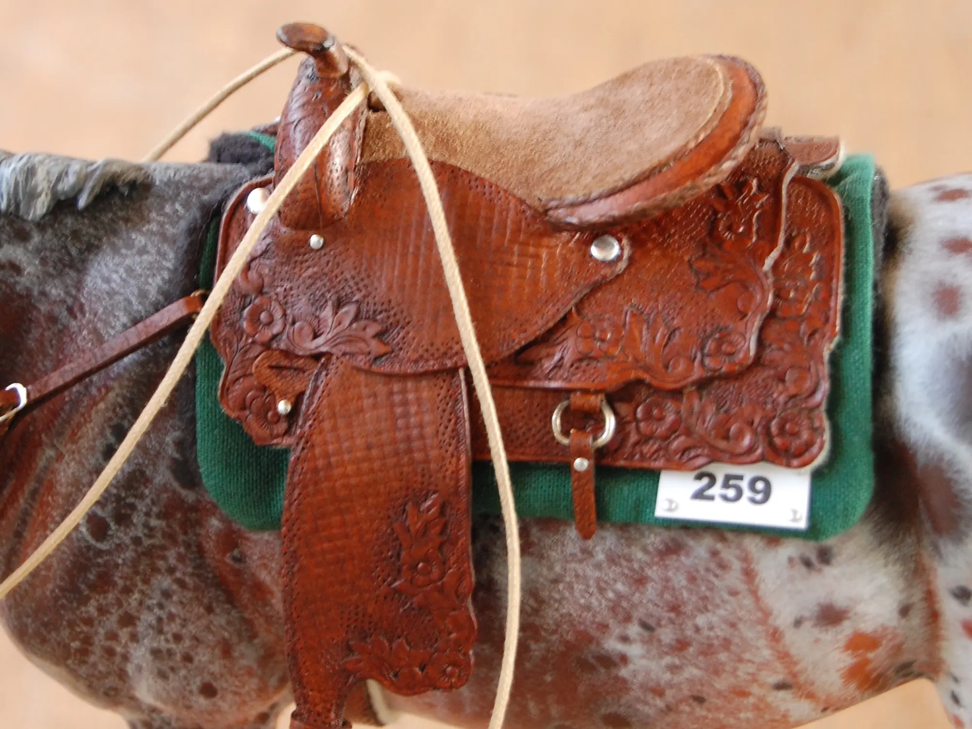 Model horse wearing miniature handmade saddle