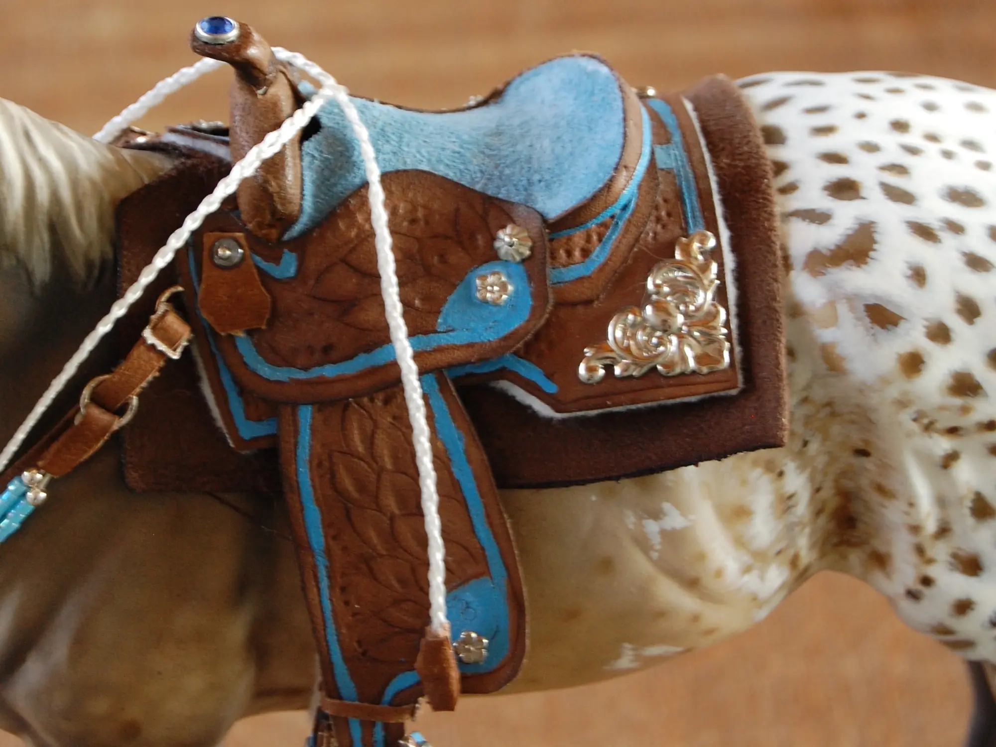 Model horse wearing miniature handmade saddle