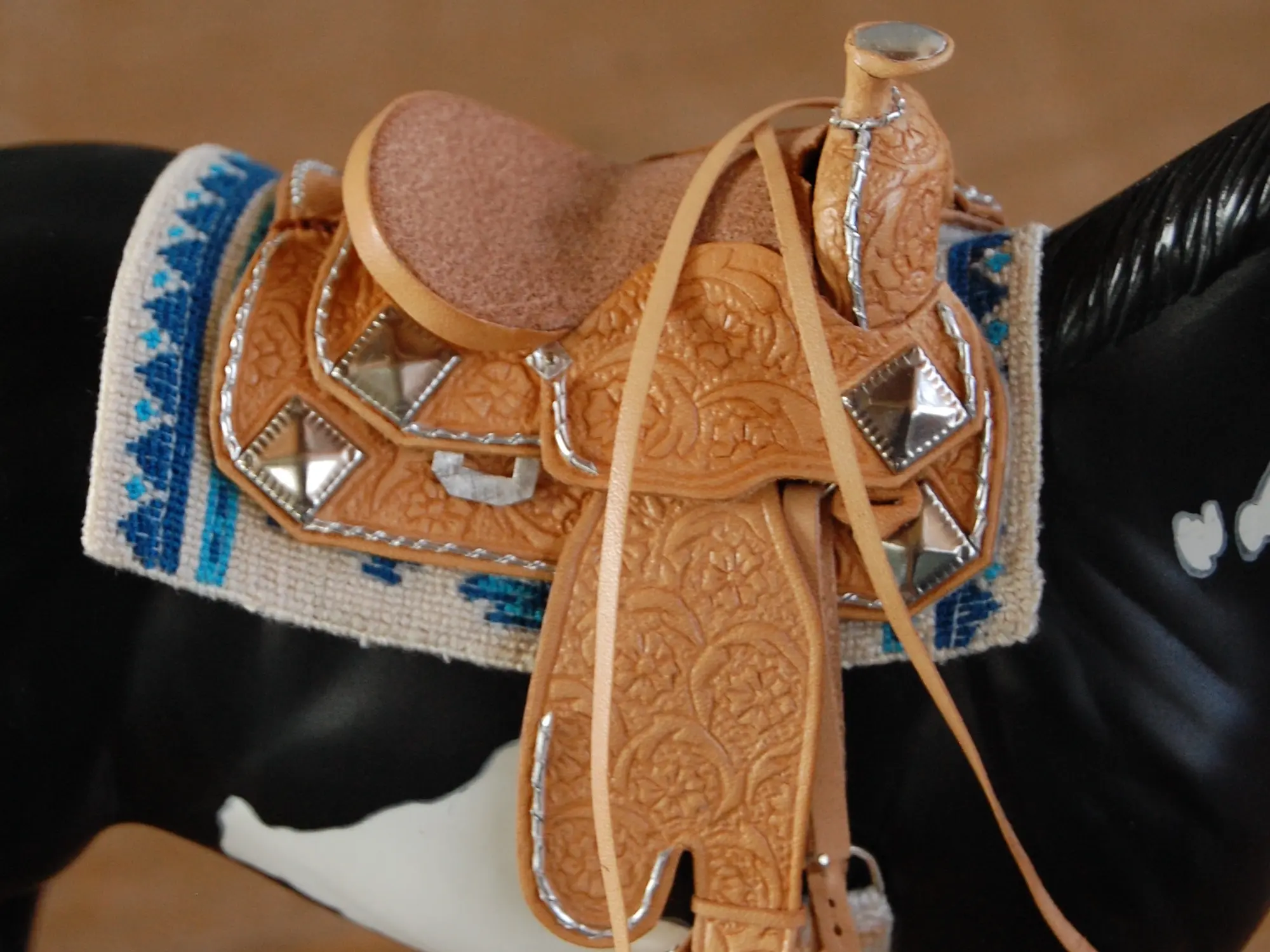 Model horse wearing miniature handmade saddle