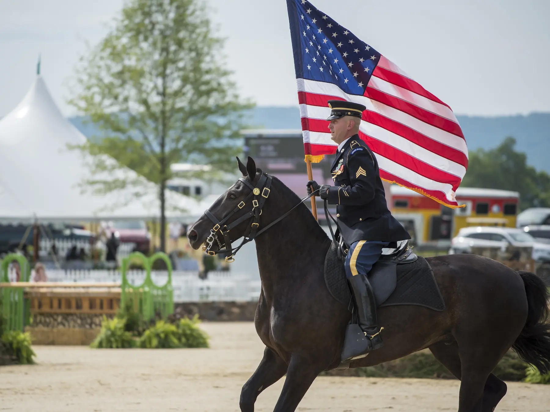 Man riding a horse carrying a US flag