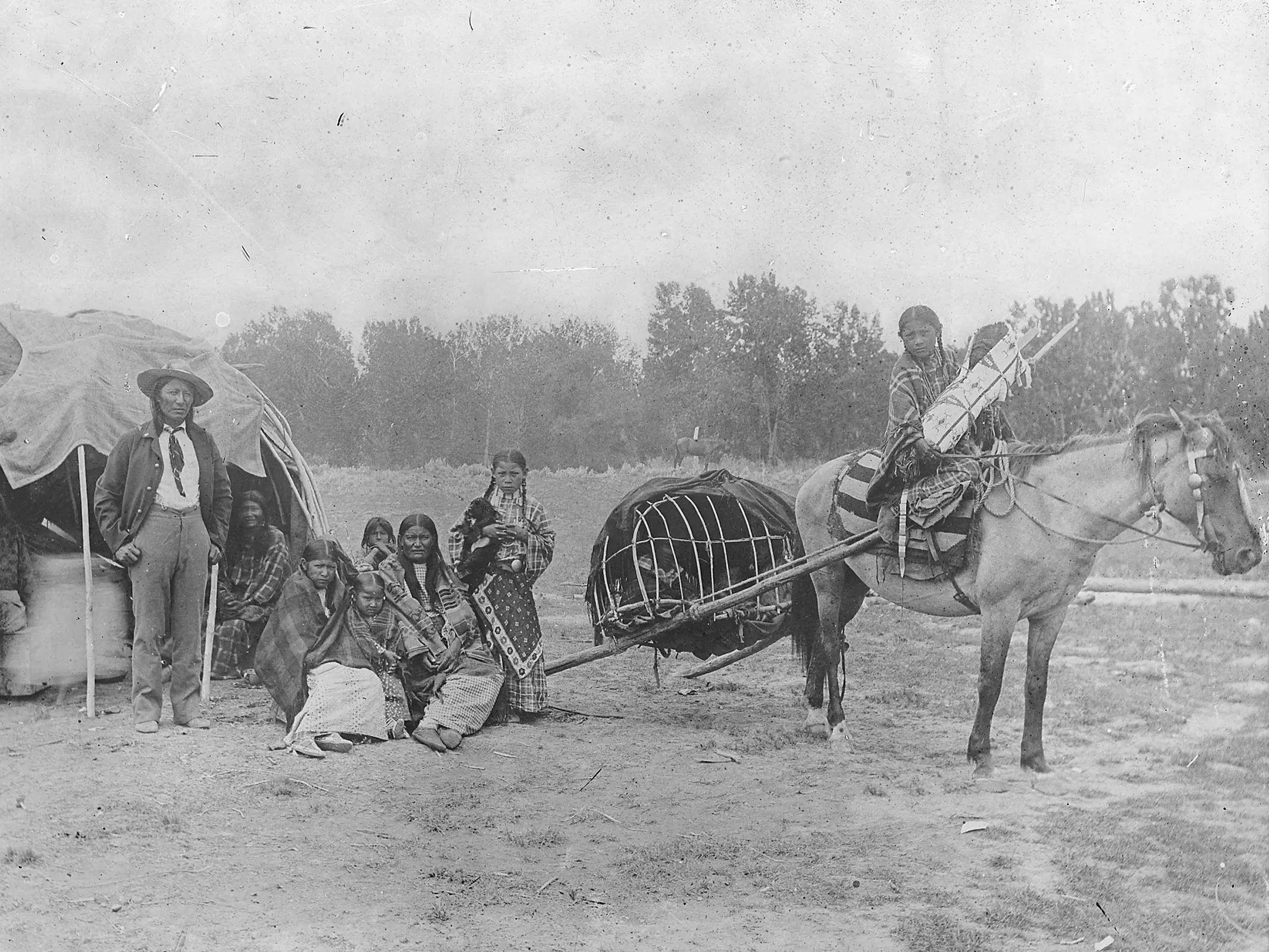 A Native American family standing with a horse in harness
