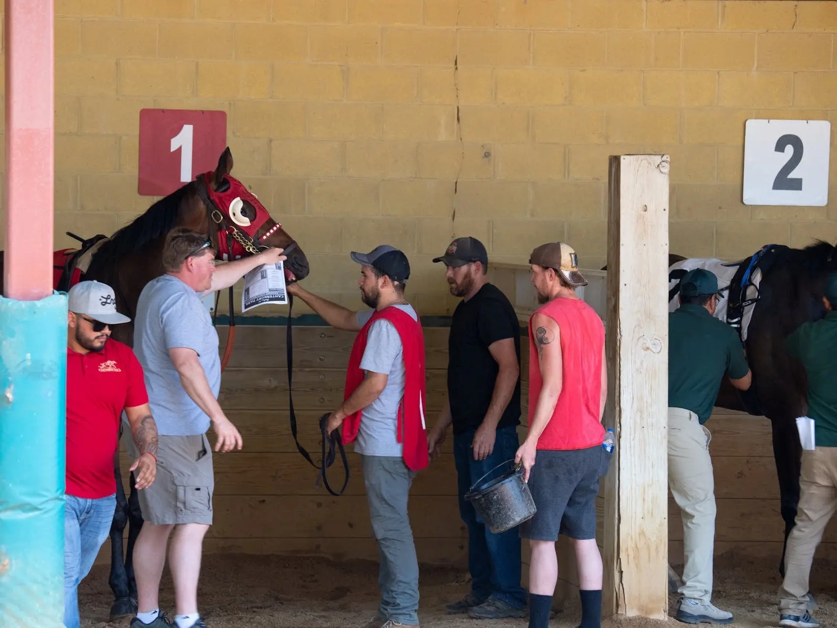 Men standing with a horse at a racetrack