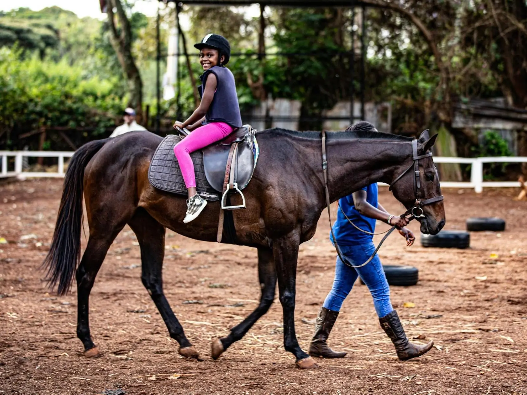 Man leading a smiling child sitting backwards on a horse