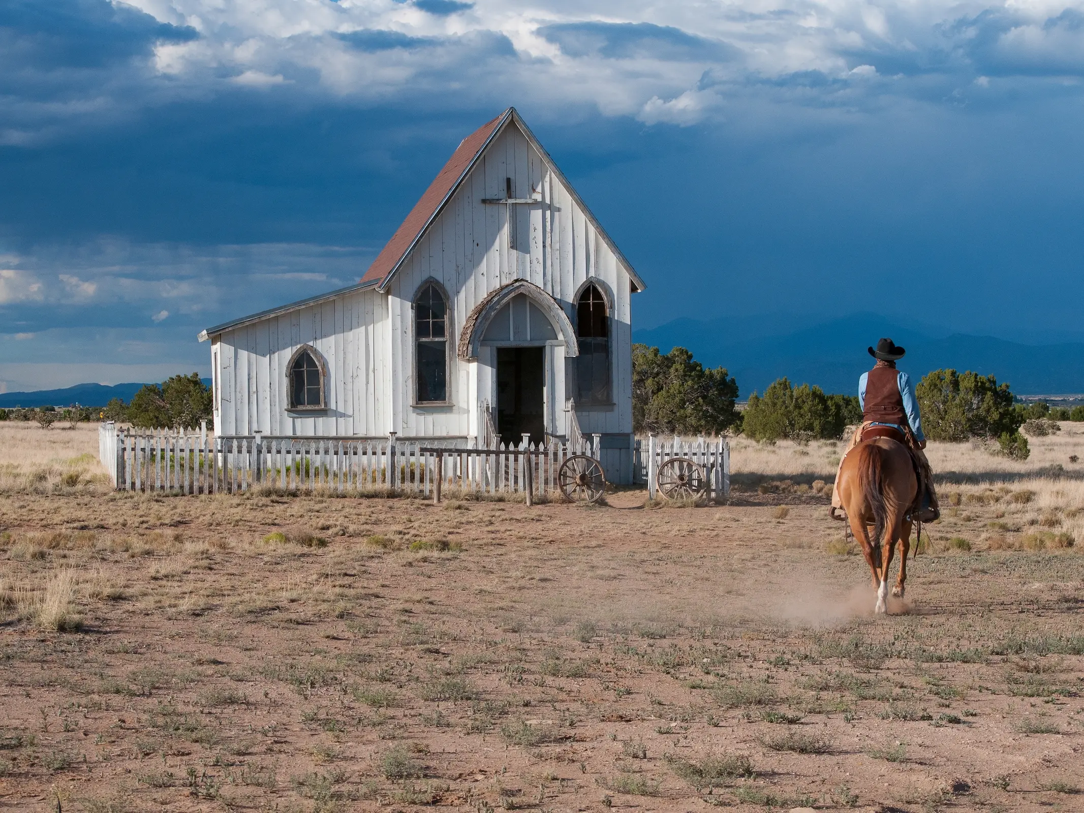 Man riding a horse to a church in the middle of nowhere